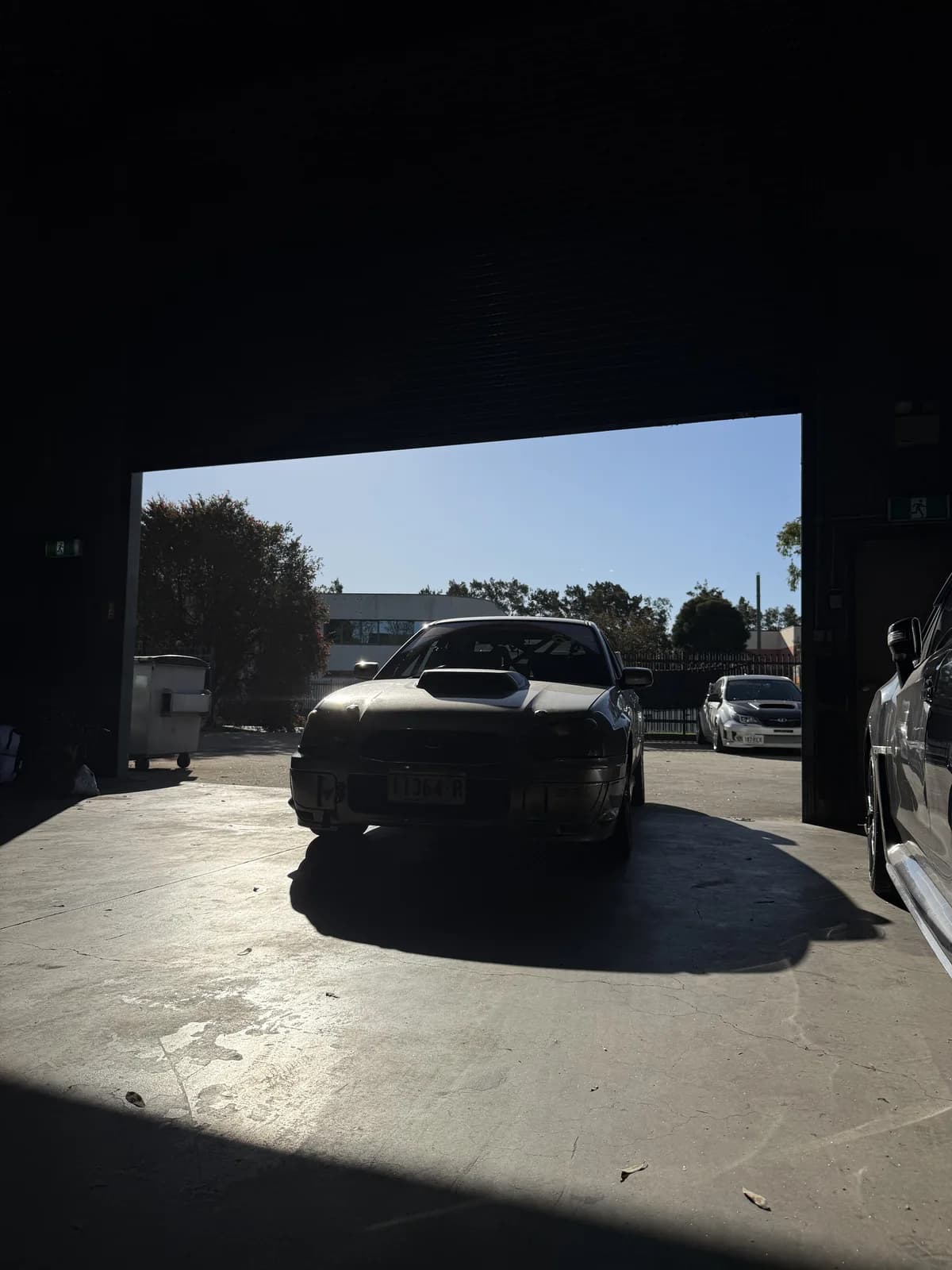 Betsy silhouetted in the workshop doorway in October 2026