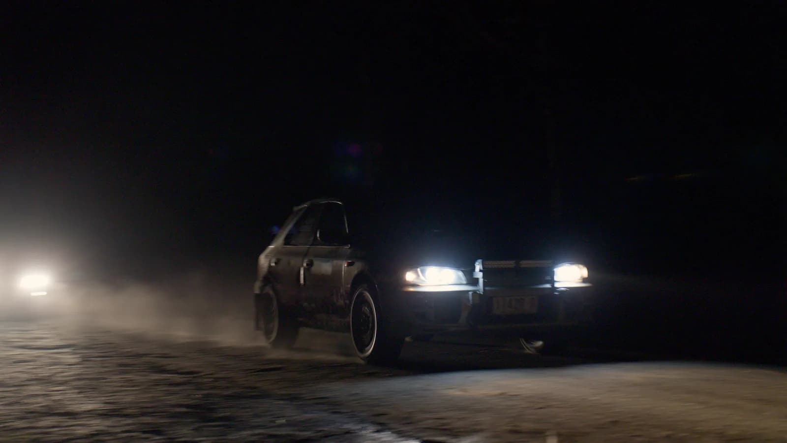 The mud-covered Impreza wagon charging through dust on a night stage at the Ada River Rally 2026