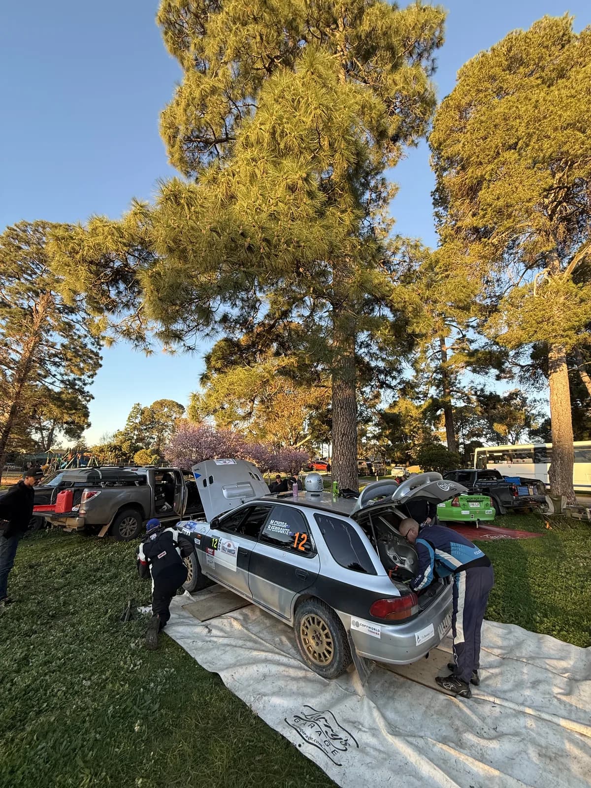 The crew around the Shakewell Racing wagon on the service tarp under the big pines at Rally Barossa