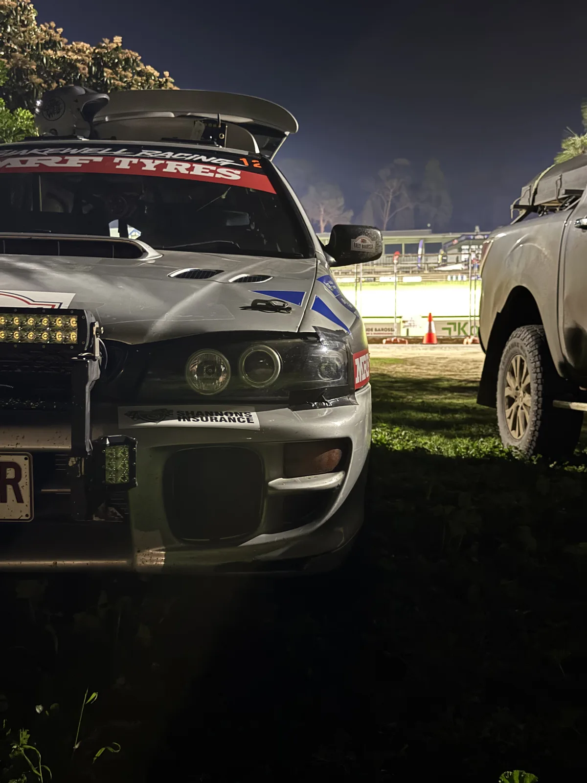 Car 12's spotlights ready for the Rally Barossa night stages, the showground lit up behind