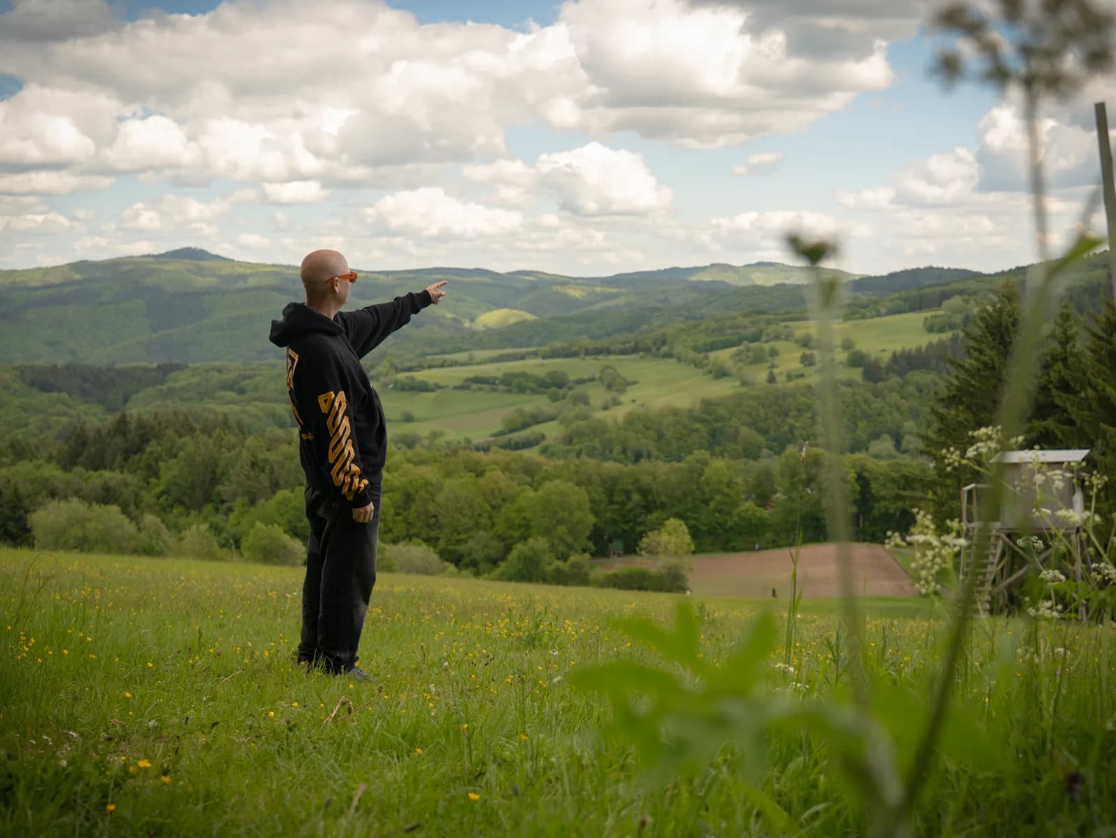 A crew member pointing out across the green Eifel hills near the Nürburgring