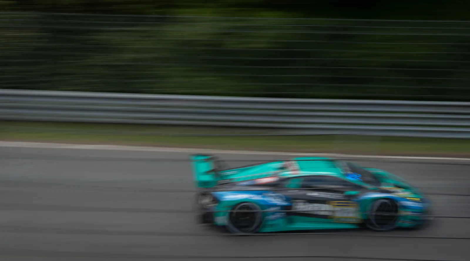 A teal GT3 car blurred at speed along the Nordschleife at the Nürburgring 24 Hours