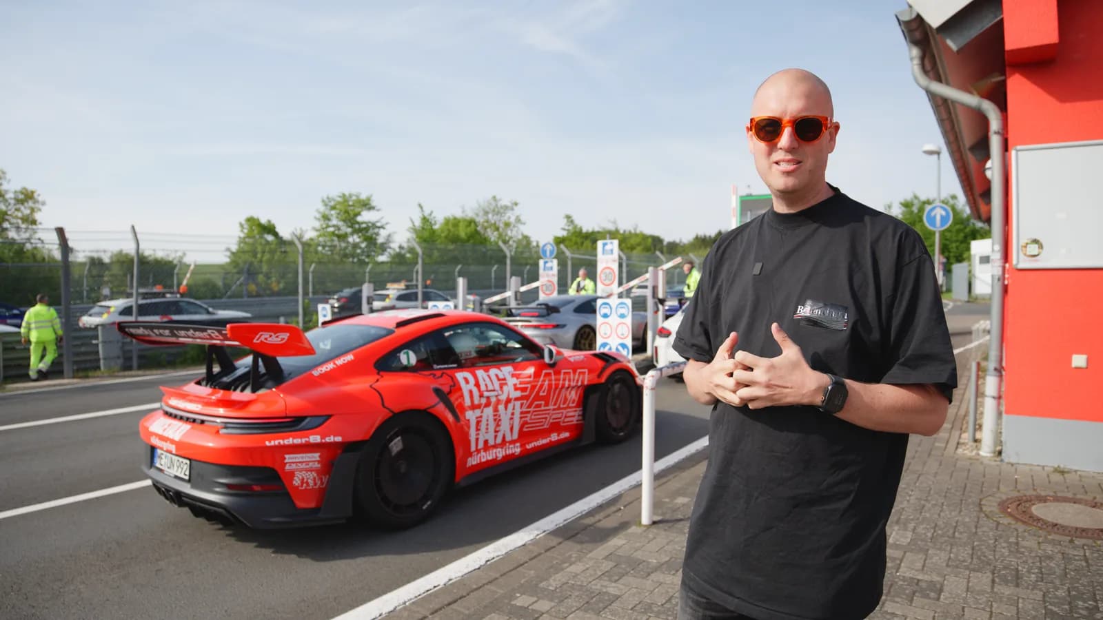 Presenting to camera beside a Porsche 911 GT3 race taxi at the Nordschleife entrance