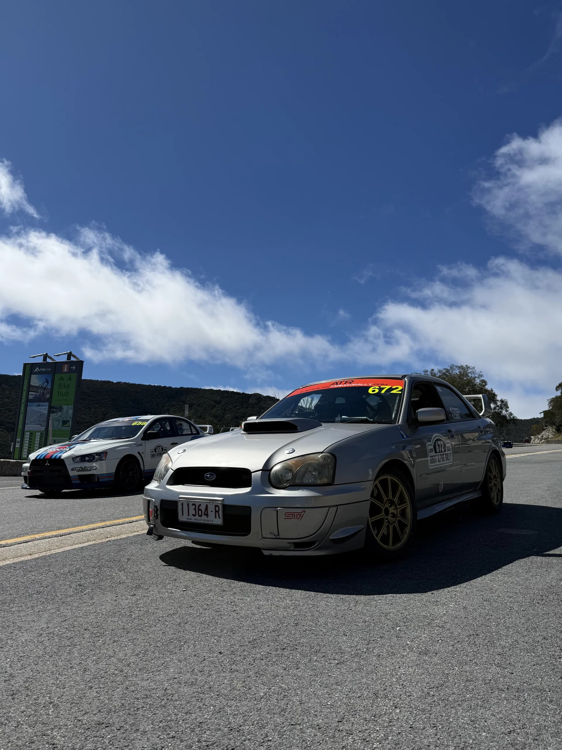 Cars queued on the road between stages at the Great Alpine Rally