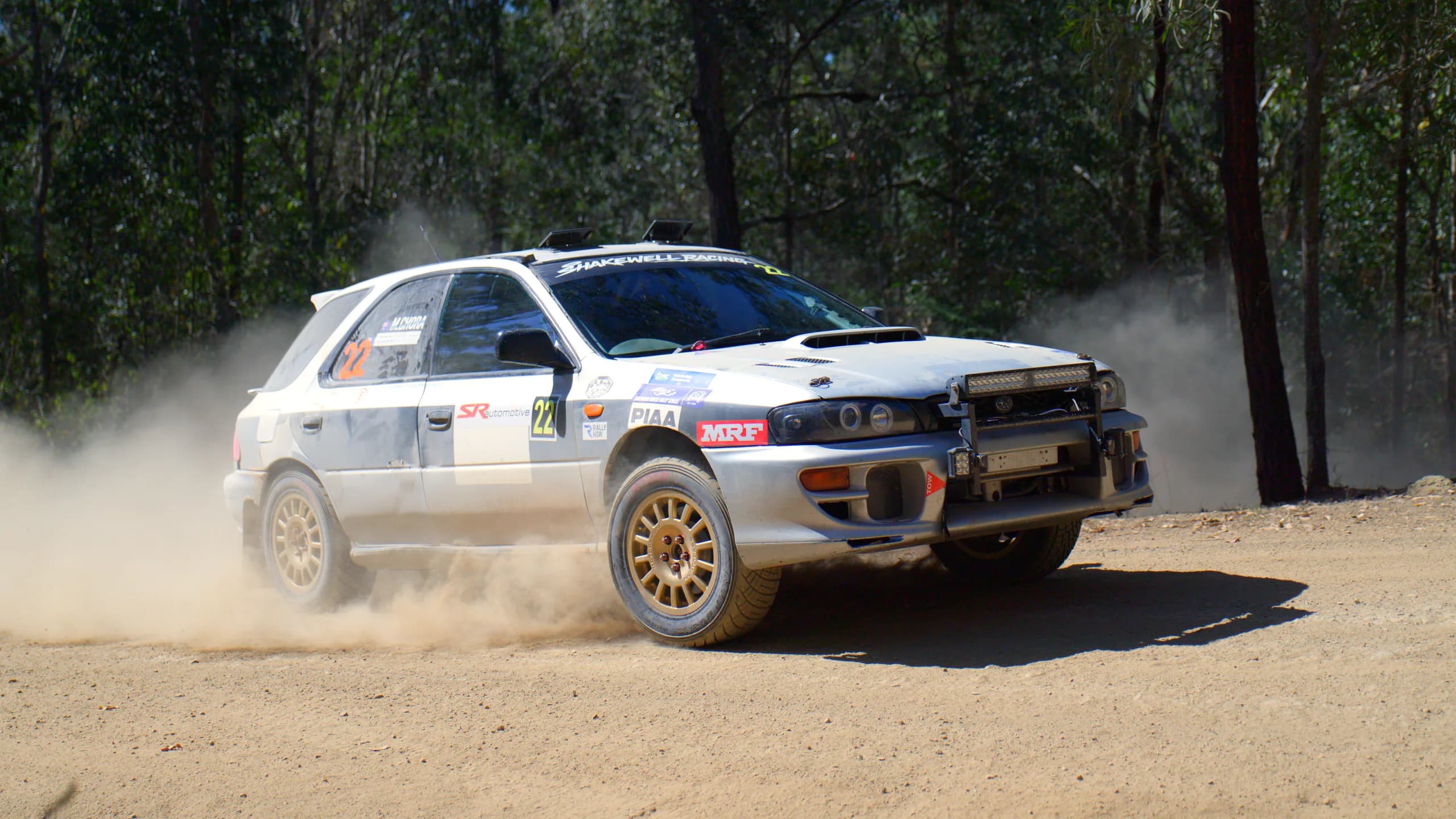 The Shakewell Racing Subaru Impreza wagon kicking up dust on a gravel forest stage at the Imbil Rally
