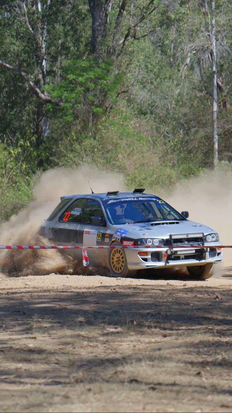 Car 22 sliding past the spectator tape on a dusty gravel stage at the Imbil Rally