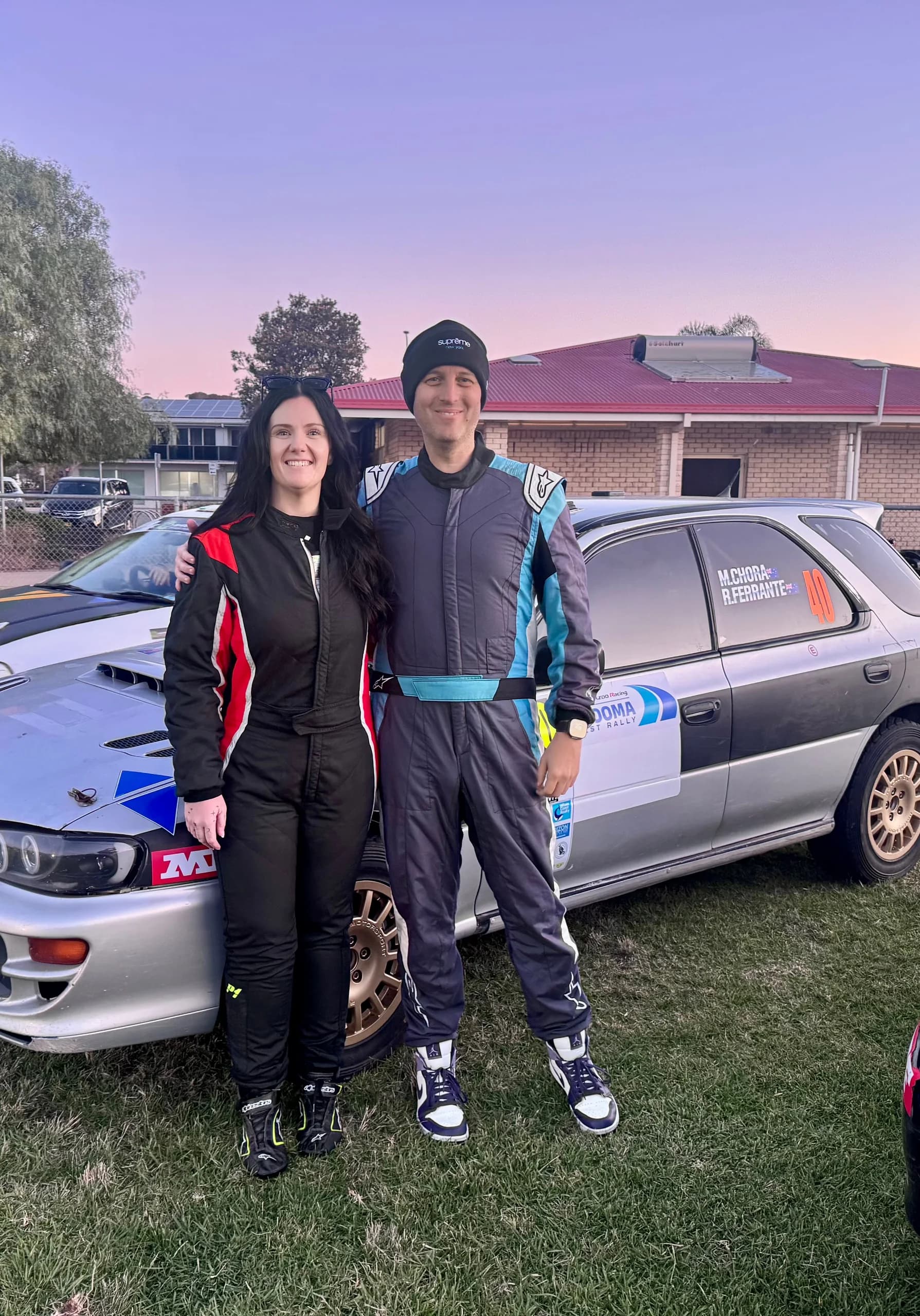 Michael Chora and Rachael Ferrante in race suits beside the rally car at the Narooma Forest Rally