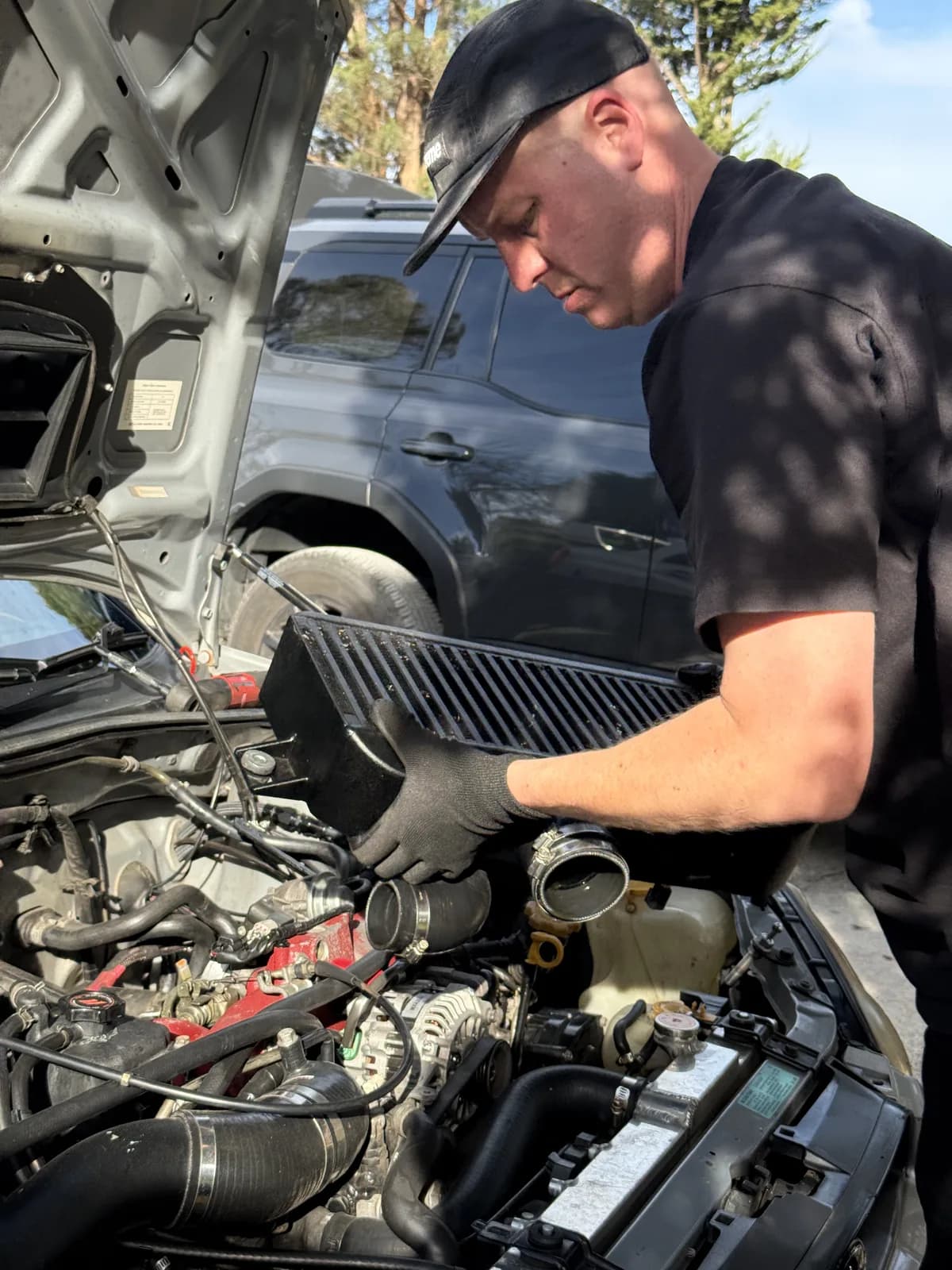 A crew member working in the engine bay of the Shakewell Racing Subaru WRX STI at the Snowy River Sprint